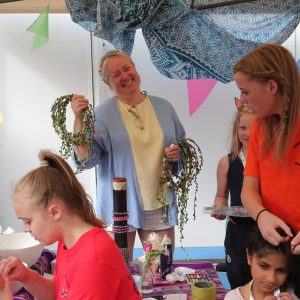 volunteer parent smiling holding up flower headbands